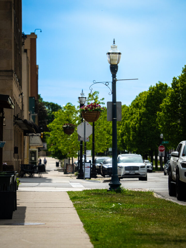 Street lamps, hanging baskets and a tree-lined sidewalk in downtown Kenosha, photographed by TMC Marketing